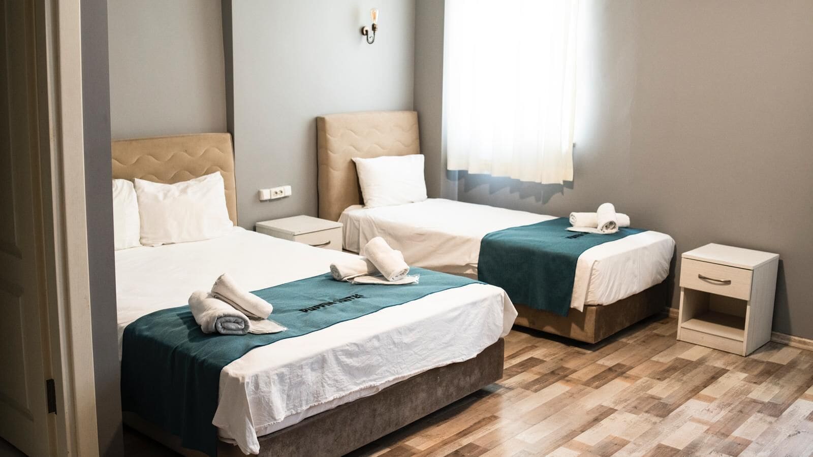 A hotel room with two beds, each with a headboard, a bedside table, and a nightstand.