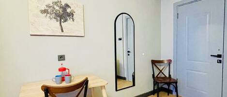 A room with a desk, two chairs, a mirror, a door, and a framed picture on the wall.