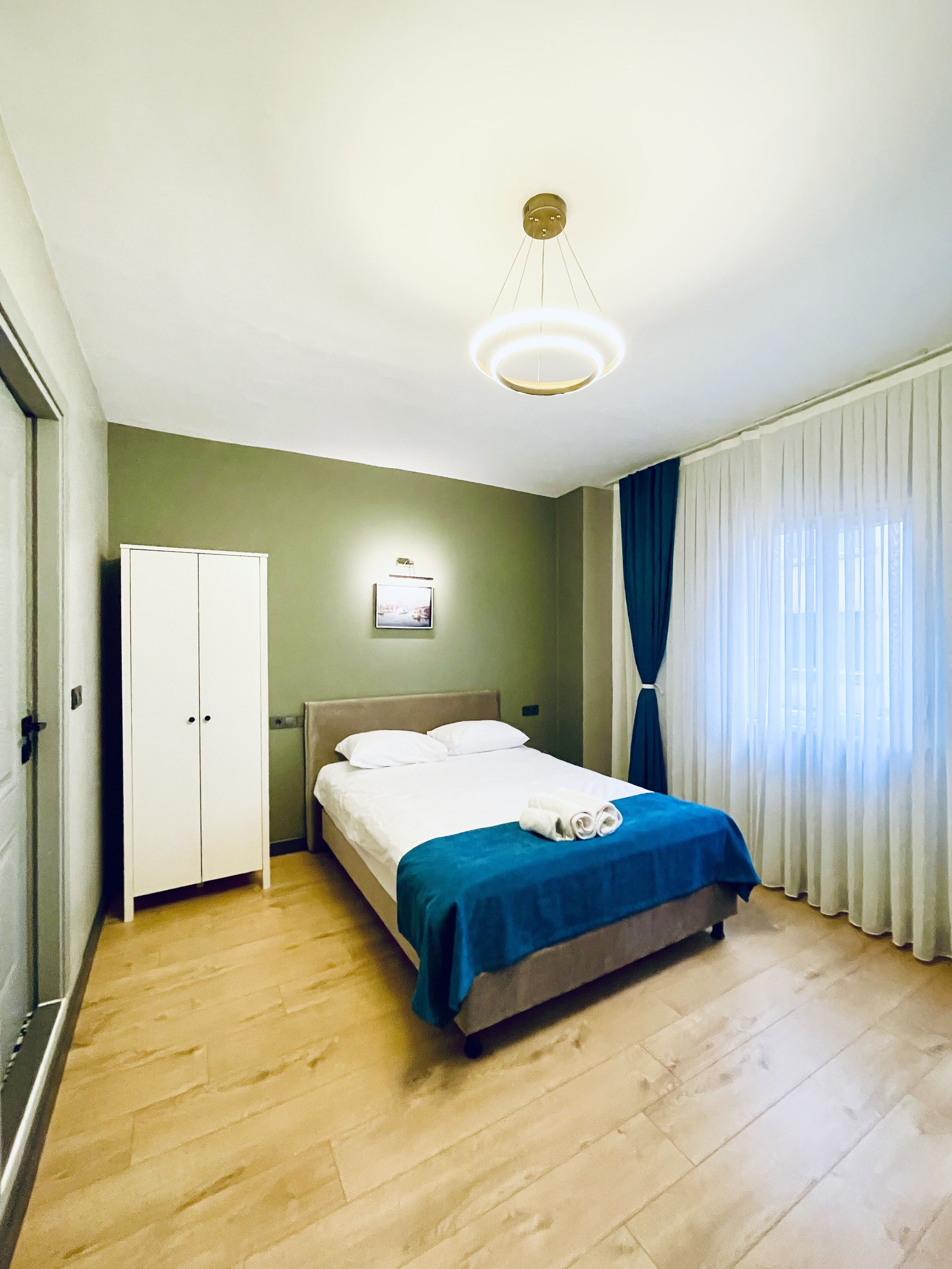 A hotel room with a bed, a wardrobe, a picture on the wall, and a curtain.
