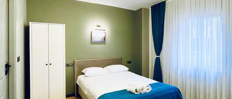 A hotel room with a bed, a wardrobe, a picture on the wall, and a curtain.