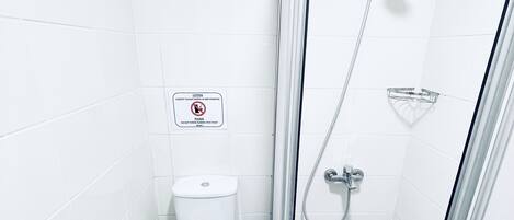 A small, modern bathroom with a toilet, a shower, and a glass-enclosed shower stall.