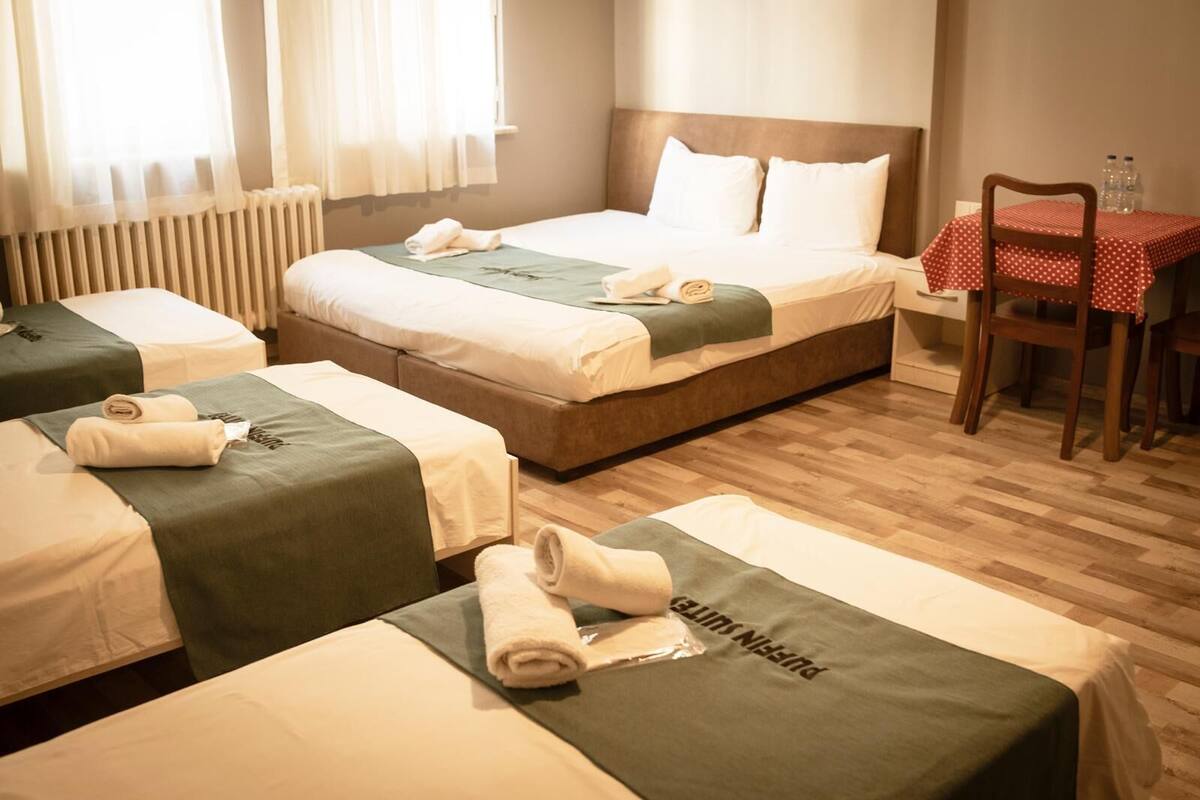 A hotel room with two beds, a dining table with chairs, and a radiator.