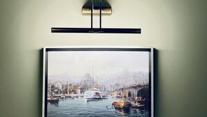 A framed painting of a harbor scene with boats and buildings.