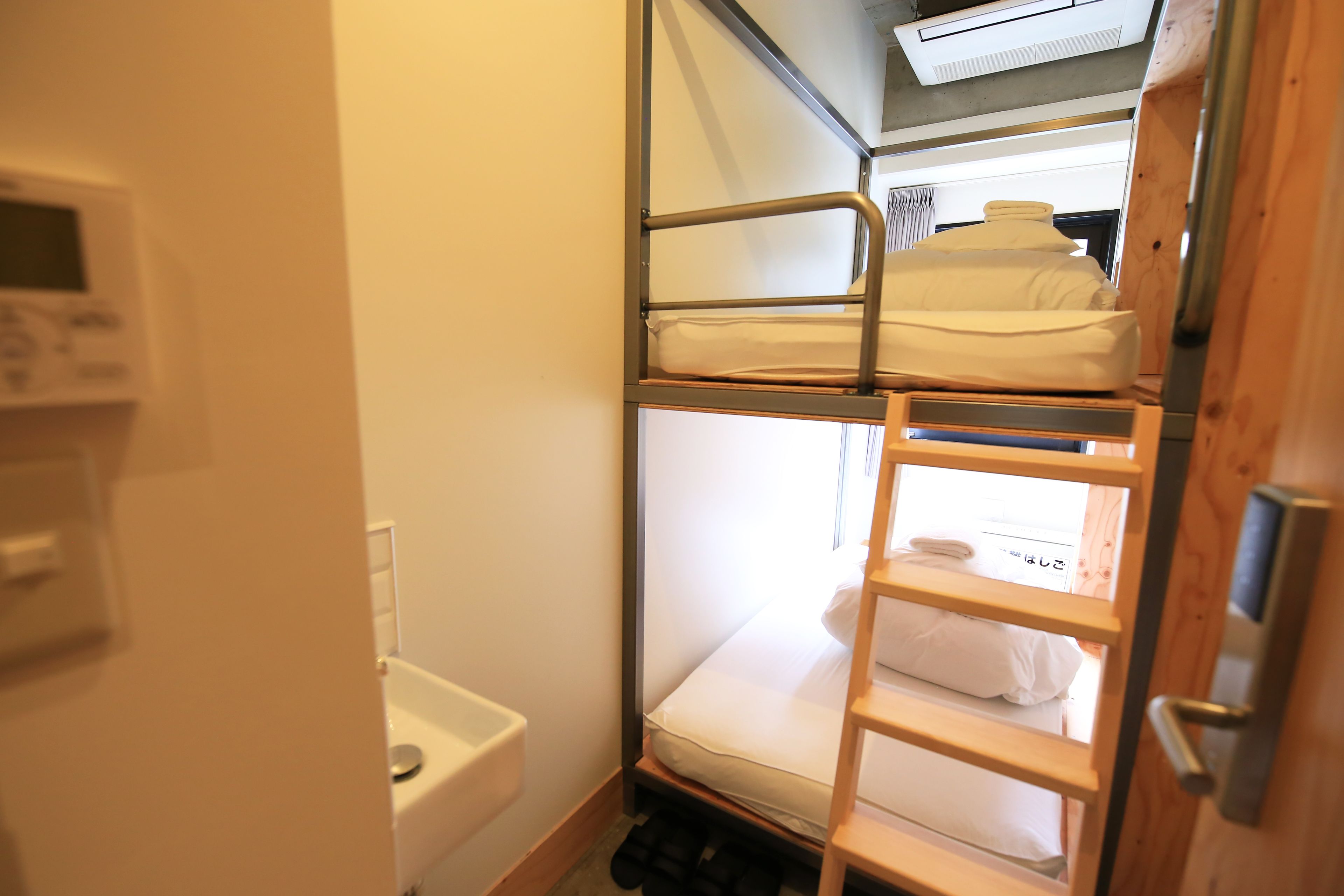 A bunk bed room with a small window, a toilet, and a microwave.