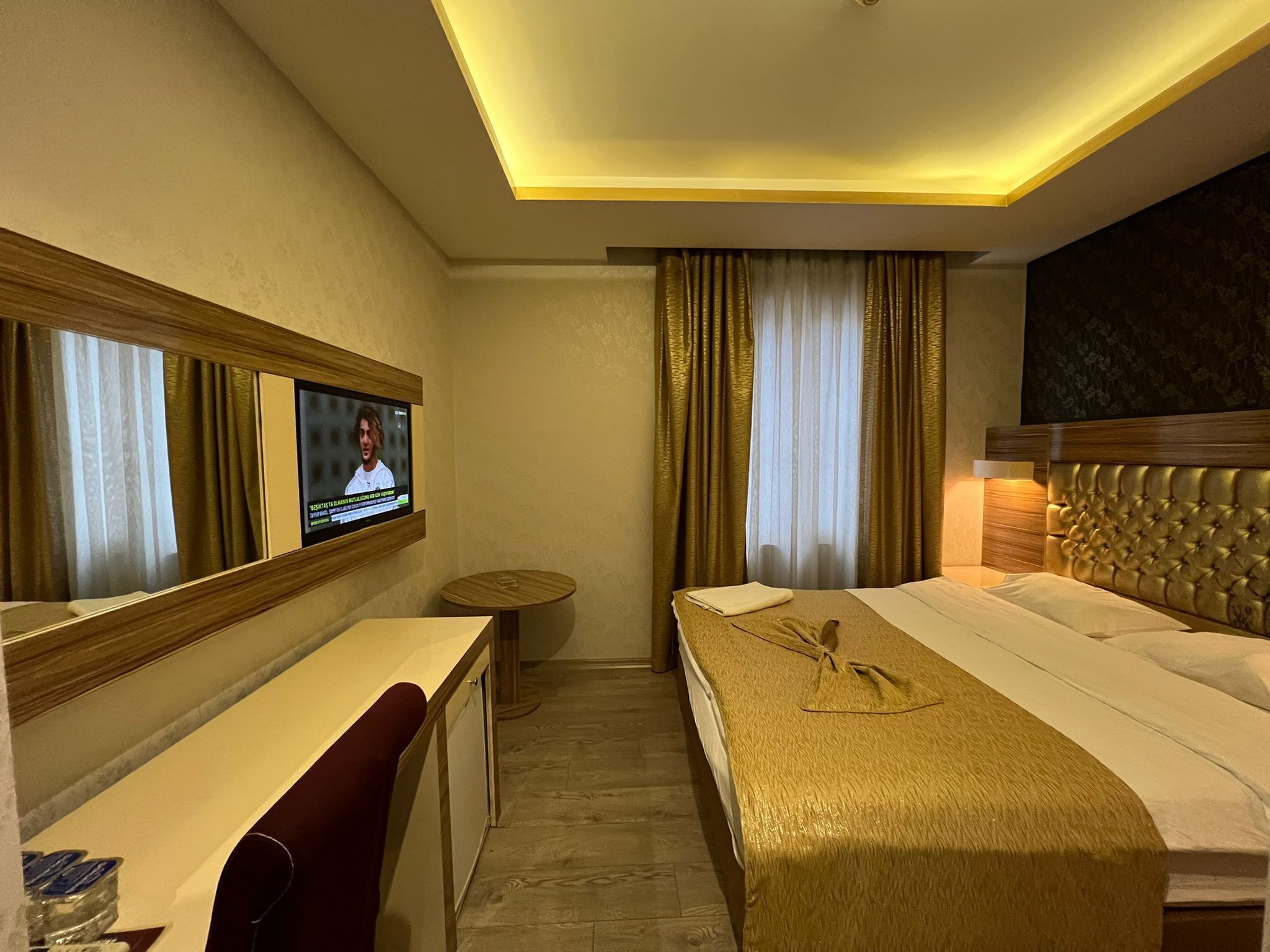 A hotel room with a bed, a desk, a TV, and a small round table.