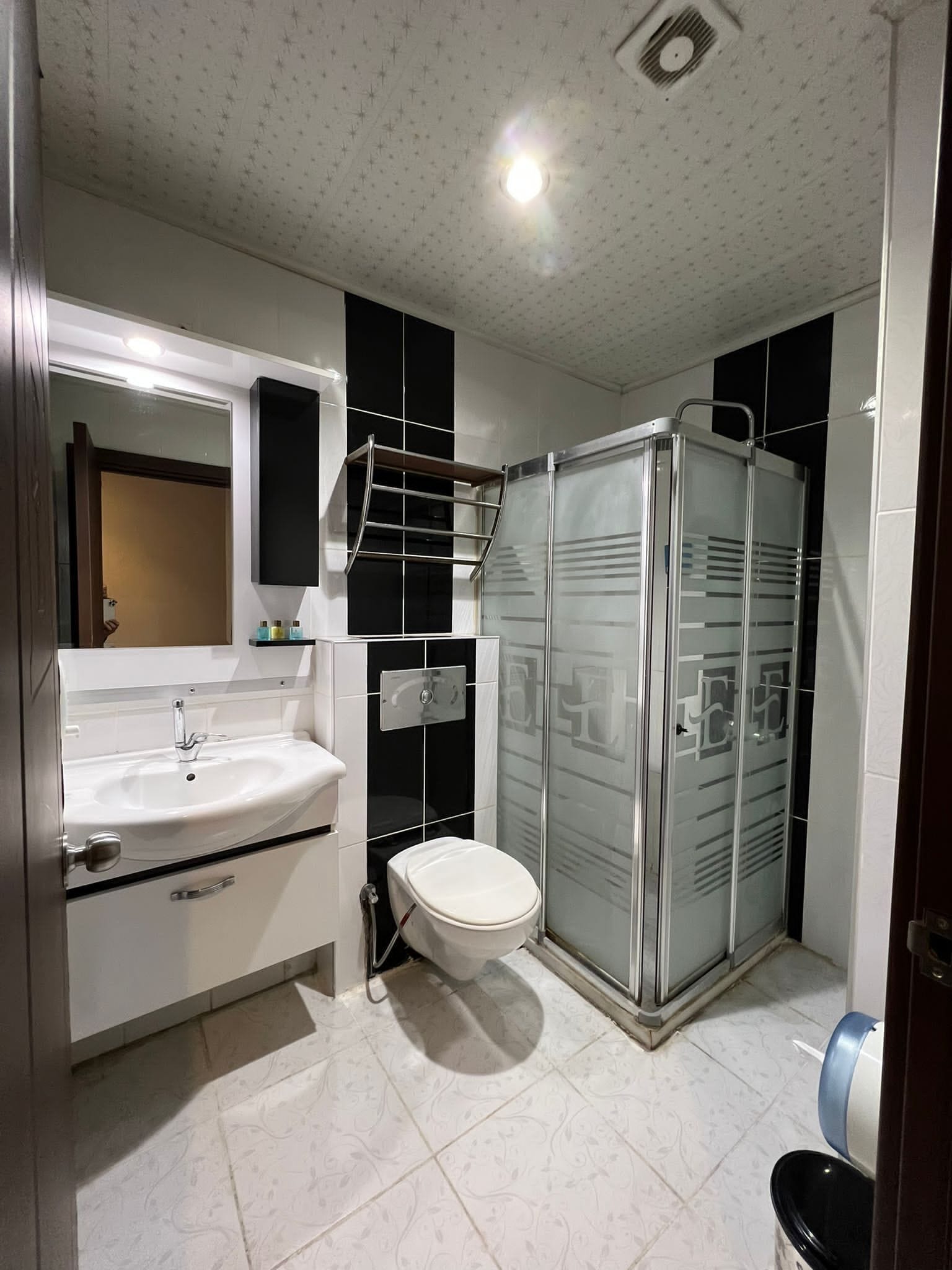 Un baño moderno con lavamanos, inodoro y ducha con mampara de vidrio.