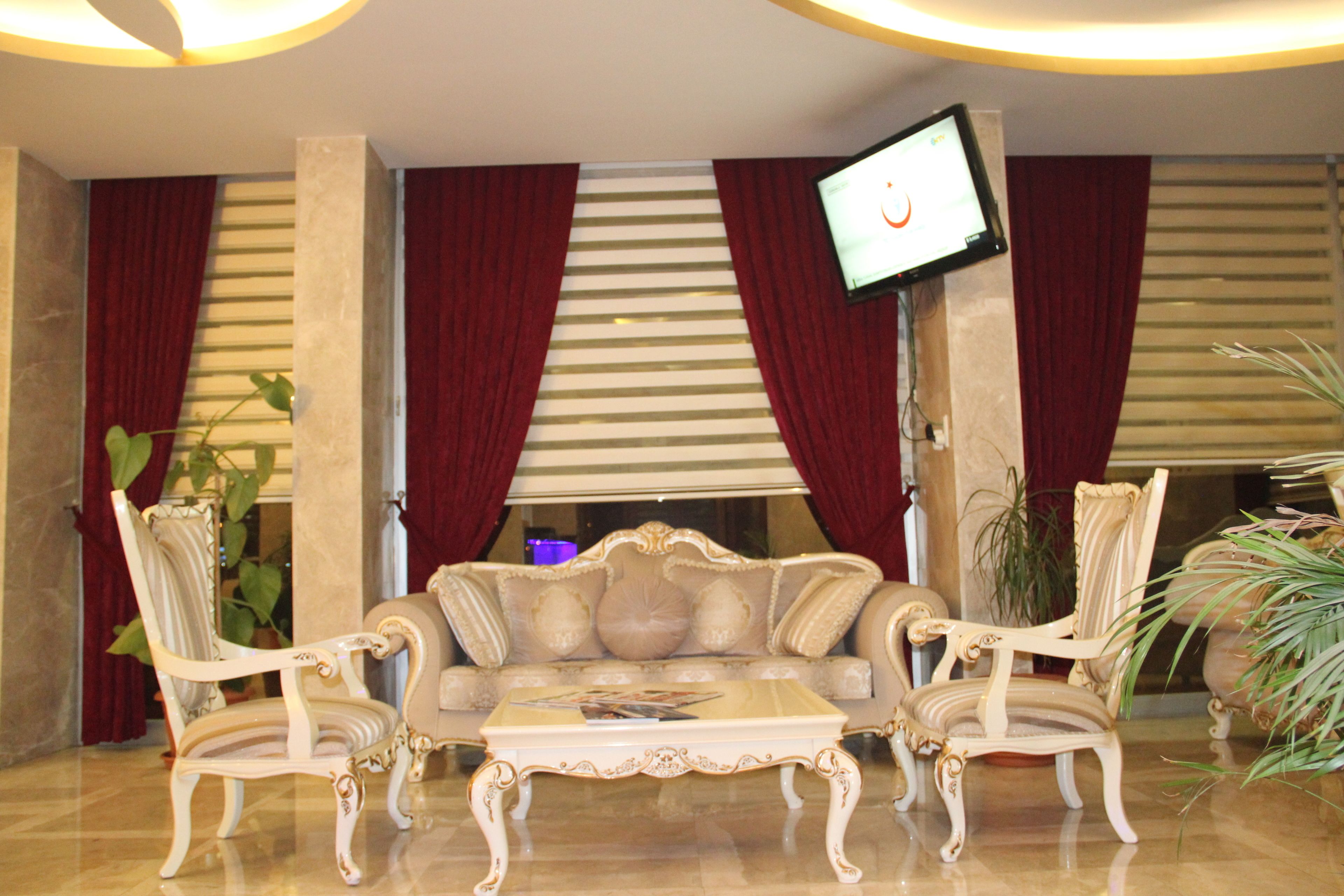 Eine luxuriöse Lobby mit einer Couch, zwei Sesseln, einem Couchtisch und einem an der Wand montierten Flachbildfernseher.