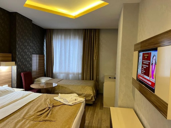 A hotel room with a bed, a desk, a chair, a TV, and a small table. - Grand Ezel Hotel (Mersin)
