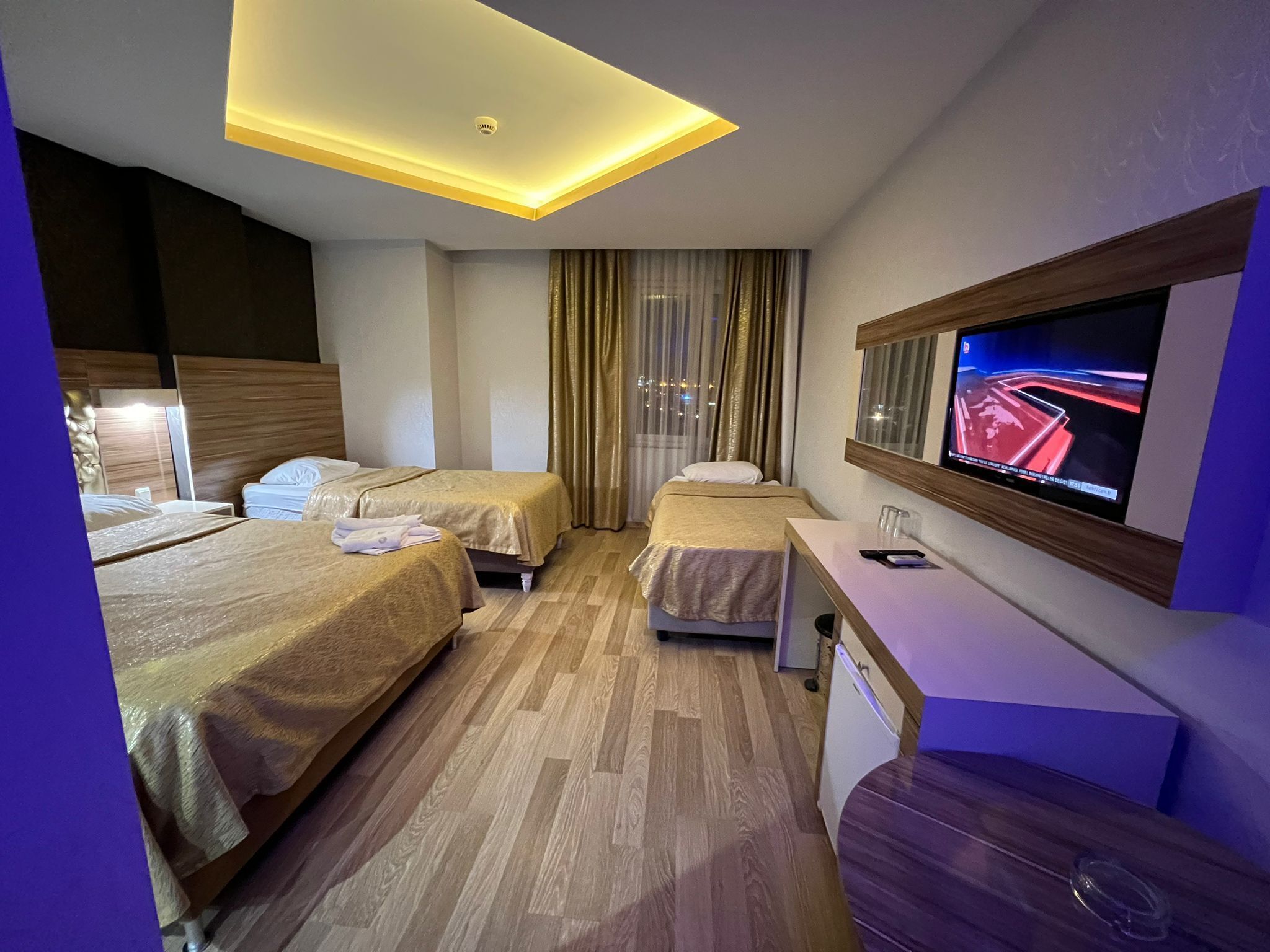 A hotel room with two beds, a television, and a desk.
