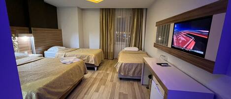 A hotel room with two beds, a television, and a desk.
