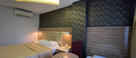 A hotel room with two single beds, a round table, and a small seating area.