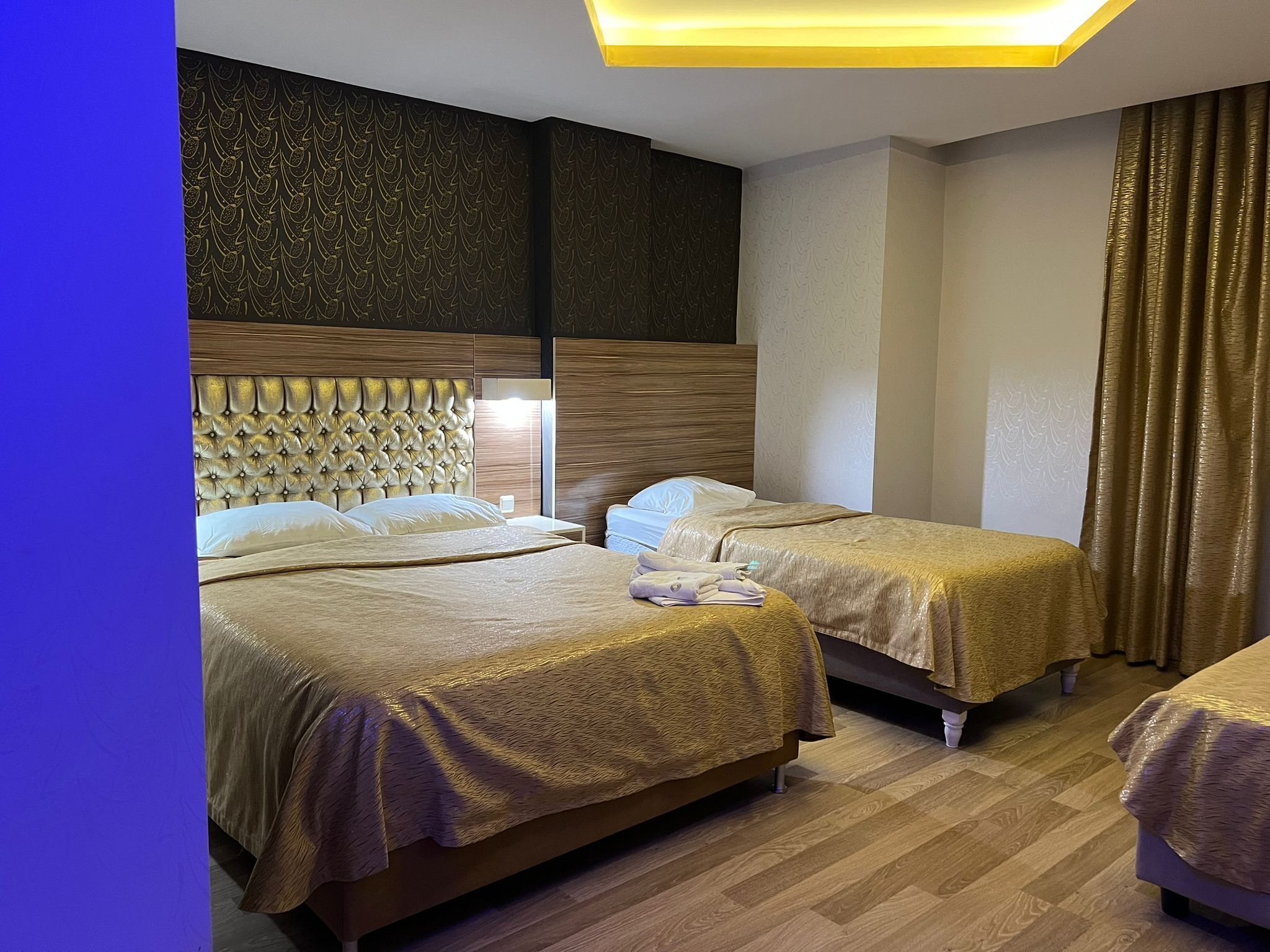 Ein Hotelzimmer mit zwei Betten, einem Kopfteil mit einer gesteppten Struktur und einer Wand mit einer Zierverkleidung.