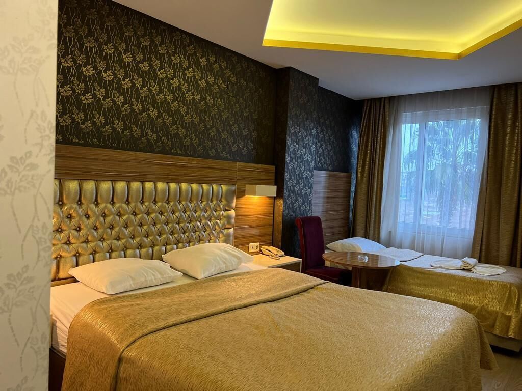 Une chambre d’hôtel avec un grand lit, une table de chevet, une chaise et une fenêtre avec des rideaux.