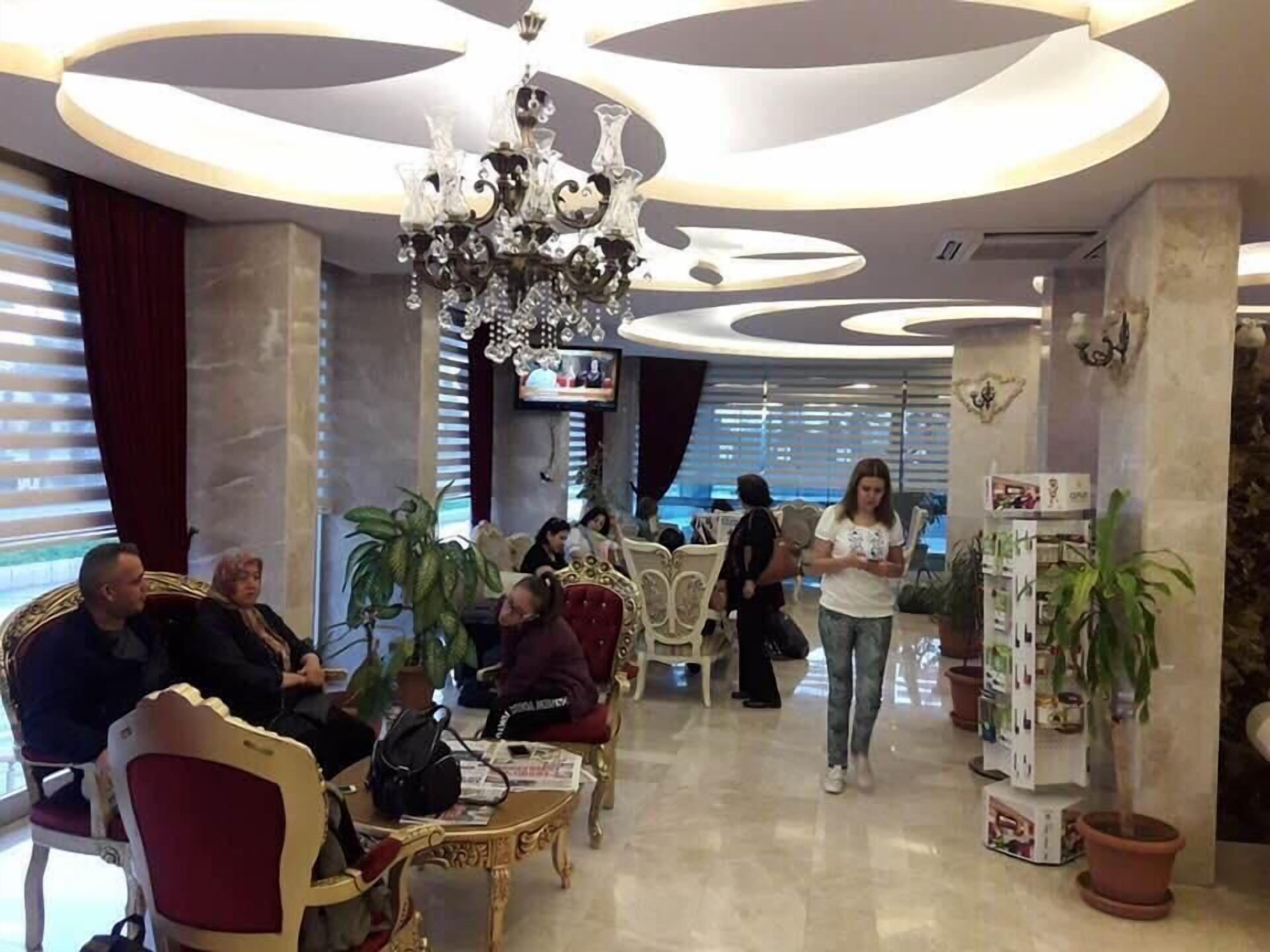 A lobby with ornate chandeliers, comfortable seating, and a television screen.