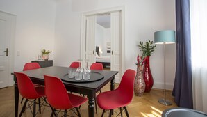 Un coin repas avec une table en bois foncé, des chaises rouges et un lampadaire au design moderne.