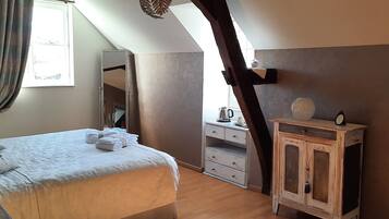 Een slaapkamer met een bed, een dressoir, een spiegel en een raam.