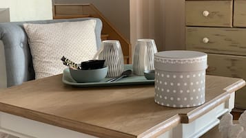 Una mesa de madera con un recipiente gris de lunares, una taza a rayas y un bol con una barra de chocolate.