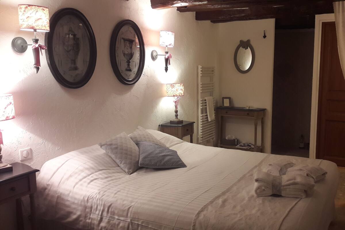 Un lit bien fait, avec des oreillers, une table de chevet, une lampe et des éléments de décoration fixés au mur.