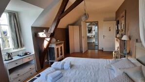 Une chambre à coucher avec un grand lit, une commode en bois, un bureau et une fenêtre avec des rideaux.