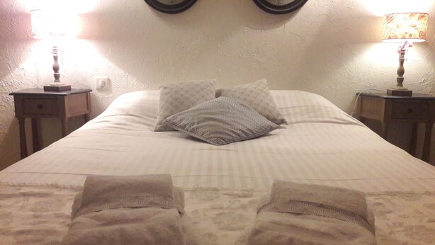 Een keurig opgemaakt bed met twee kussens en twee handdoeken.