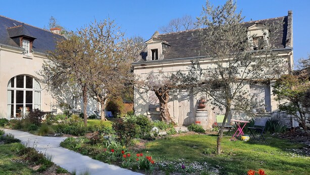 Un bâtiment historique doté d’un jardin avec un sentier, de grandes fenêtres et d’une statue.