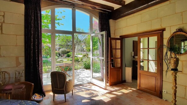 Une pièce dotée d’une grande porte vitrée donnant sur un jardin, d’une porte en bois et d’un miroir mural.