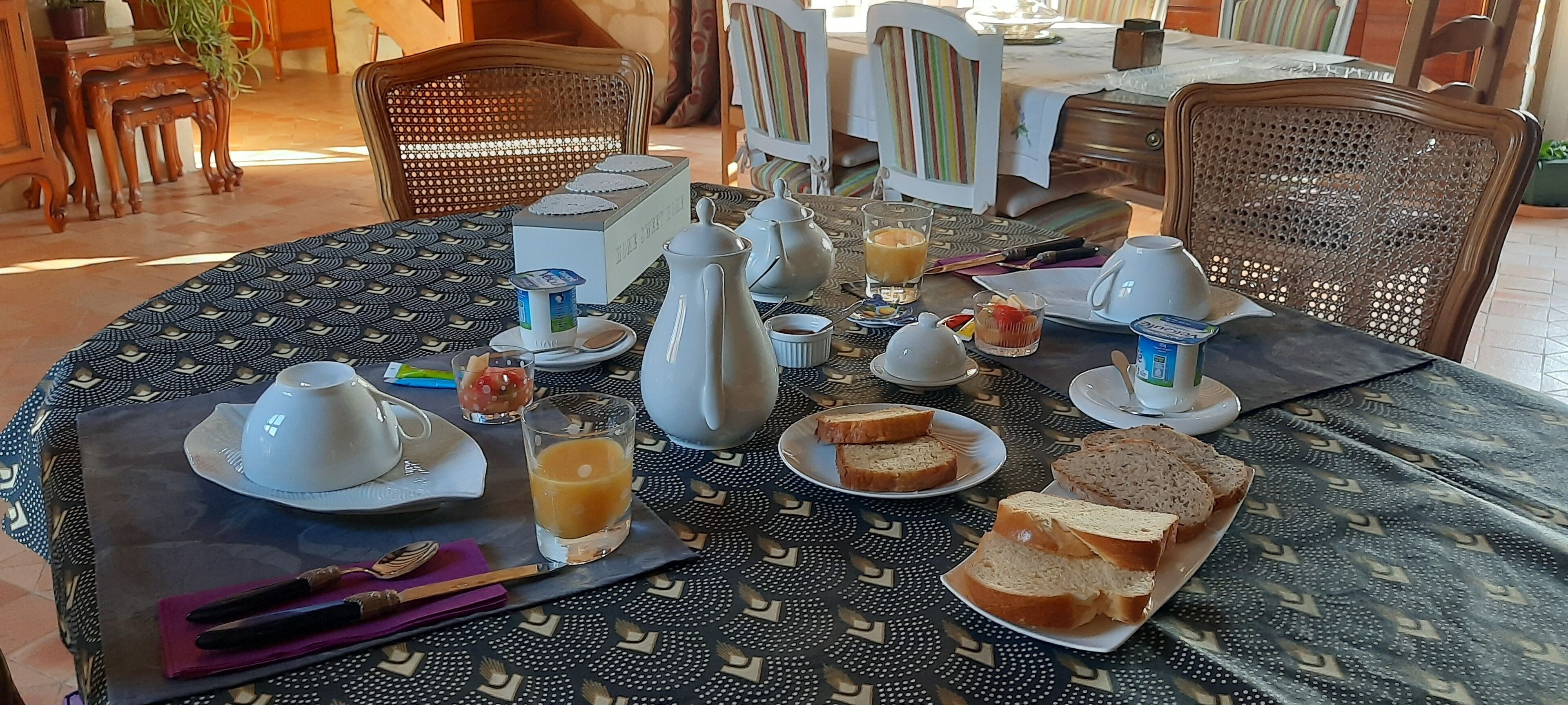 A breakfast table set with plates, glasses, and bread.