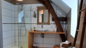 Une salle de bain moderne avec une douche à parois de verre, un meuble-lavabo en bois et un puits de lumière.
