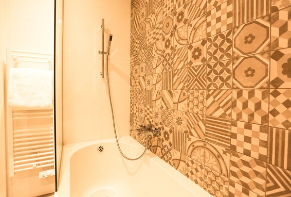 A bathroom with a bathtub, a shower, and a towel rack.