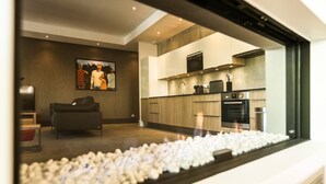 A modern kitchen with built-in appliances, a dining area with a sofa, and a fireplace. - Le Kube Annecy Appartements De Luxe (Annecy)