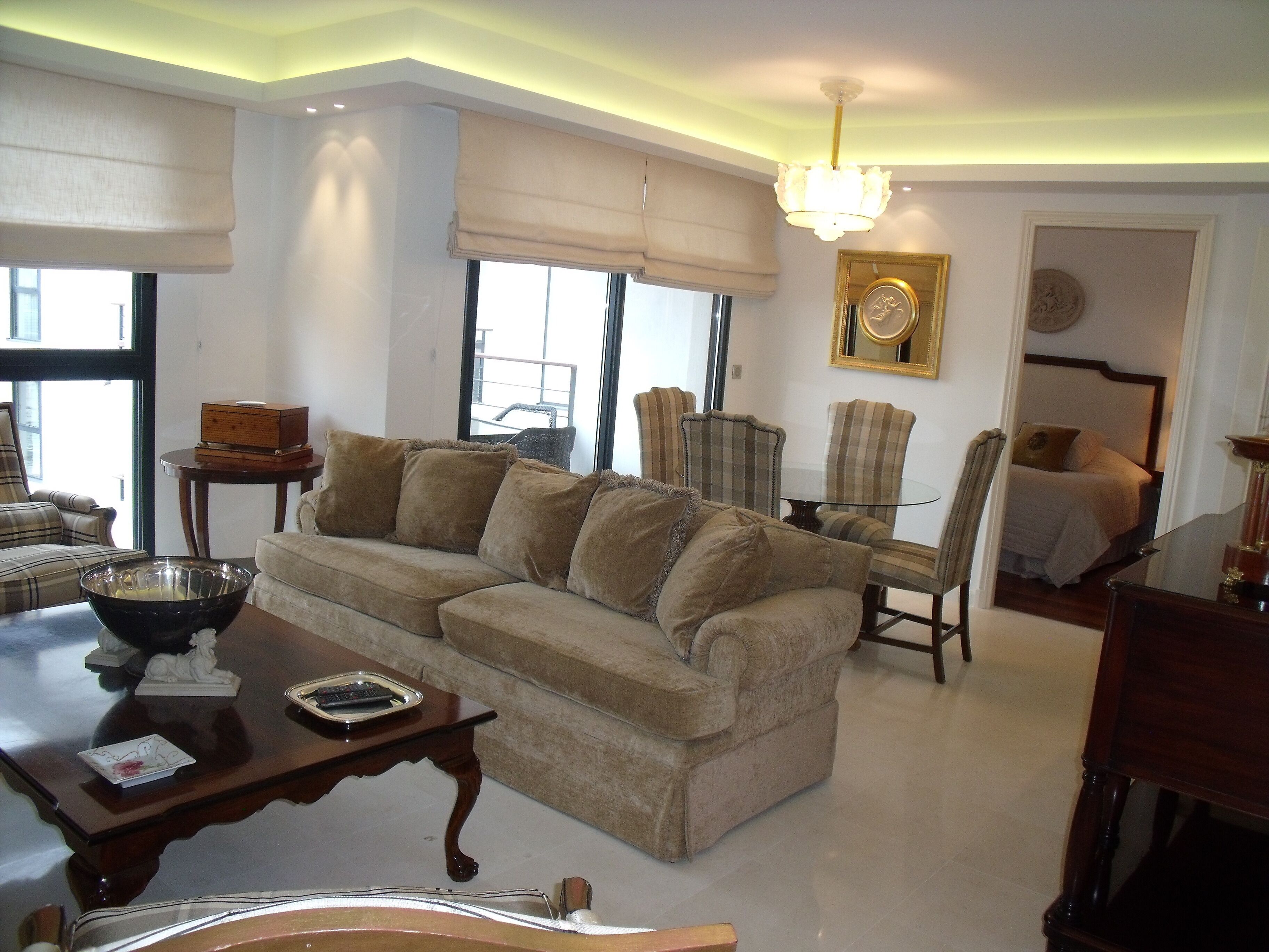 A living room with a sofa, armchairs, a coffee table, and a dining table.