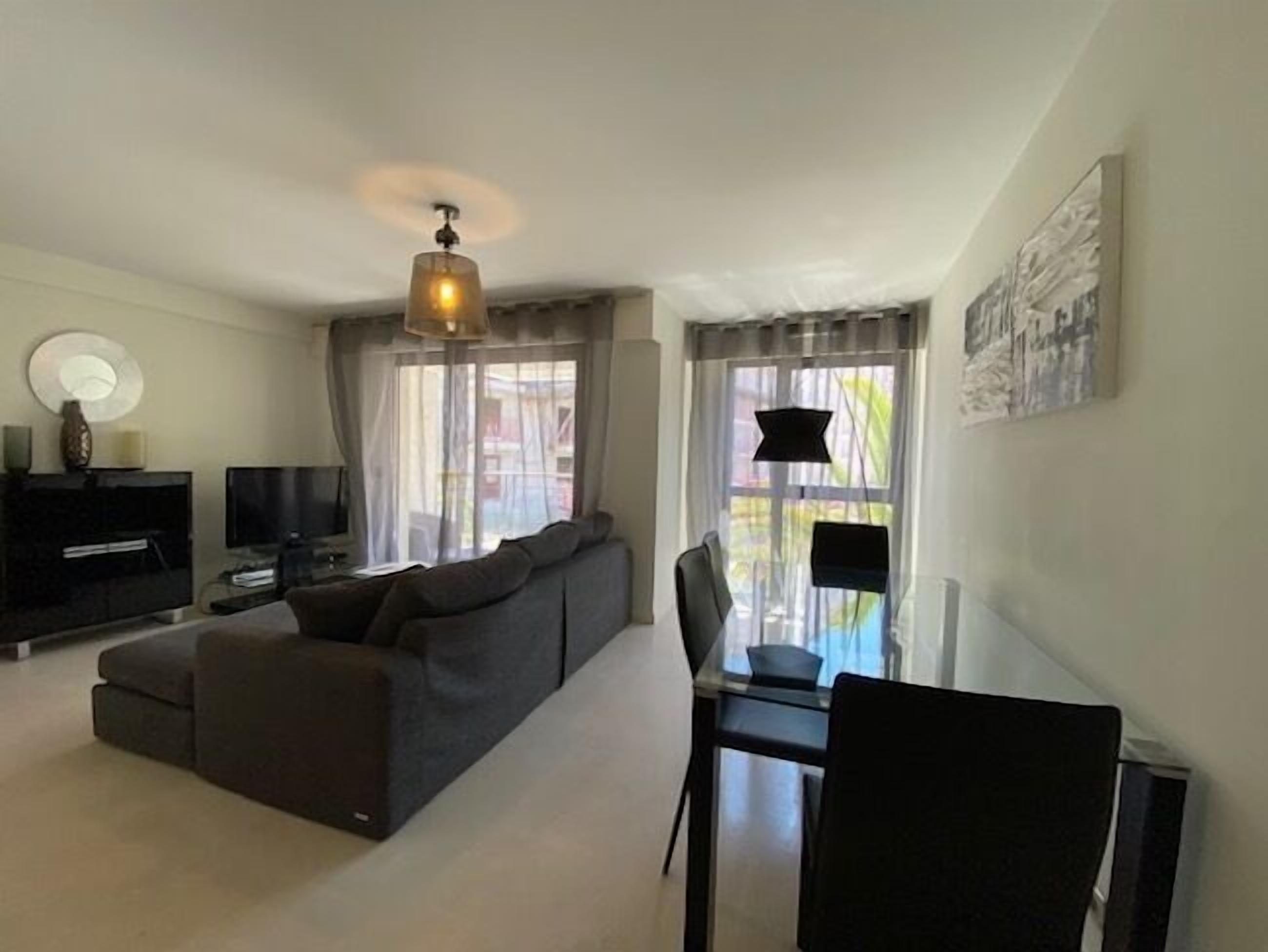 A modern living room with a sofa, TV, and dining area.