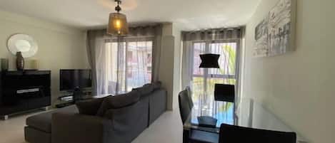 A modern living room with a sofa, TV, and dining area.