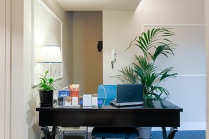 A desk with a laptop, a lamp, a potted plant, and some brochures. - Relais Tosinghi (Florence)