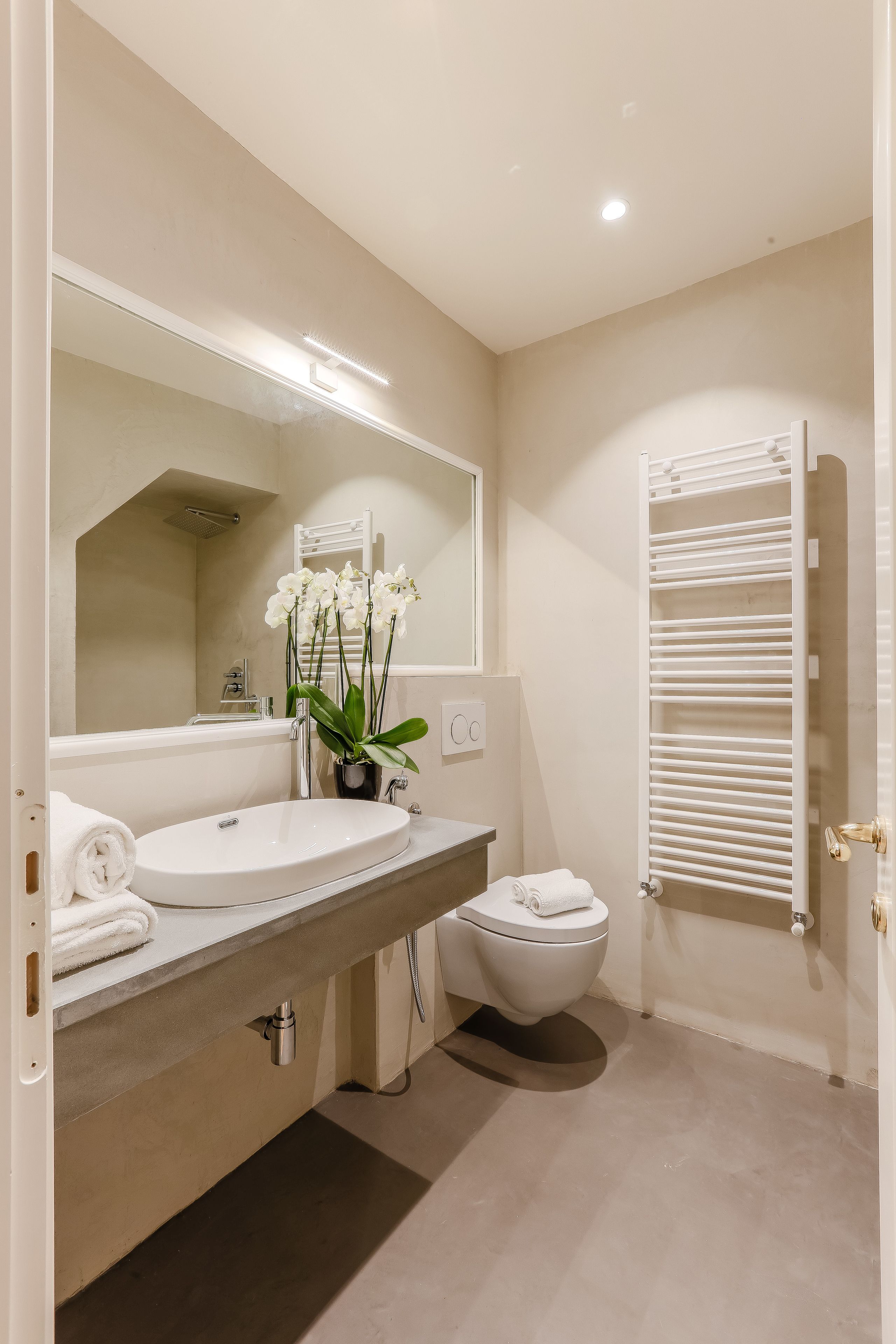 Une salle de bain avec un lavabo blanc, un miroir, des toilettes et un porte-serviettes.