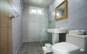 A modern bathroom with grey tiles, a white sink, a toilet, and a shower area. - Tilda House (Jeju City)