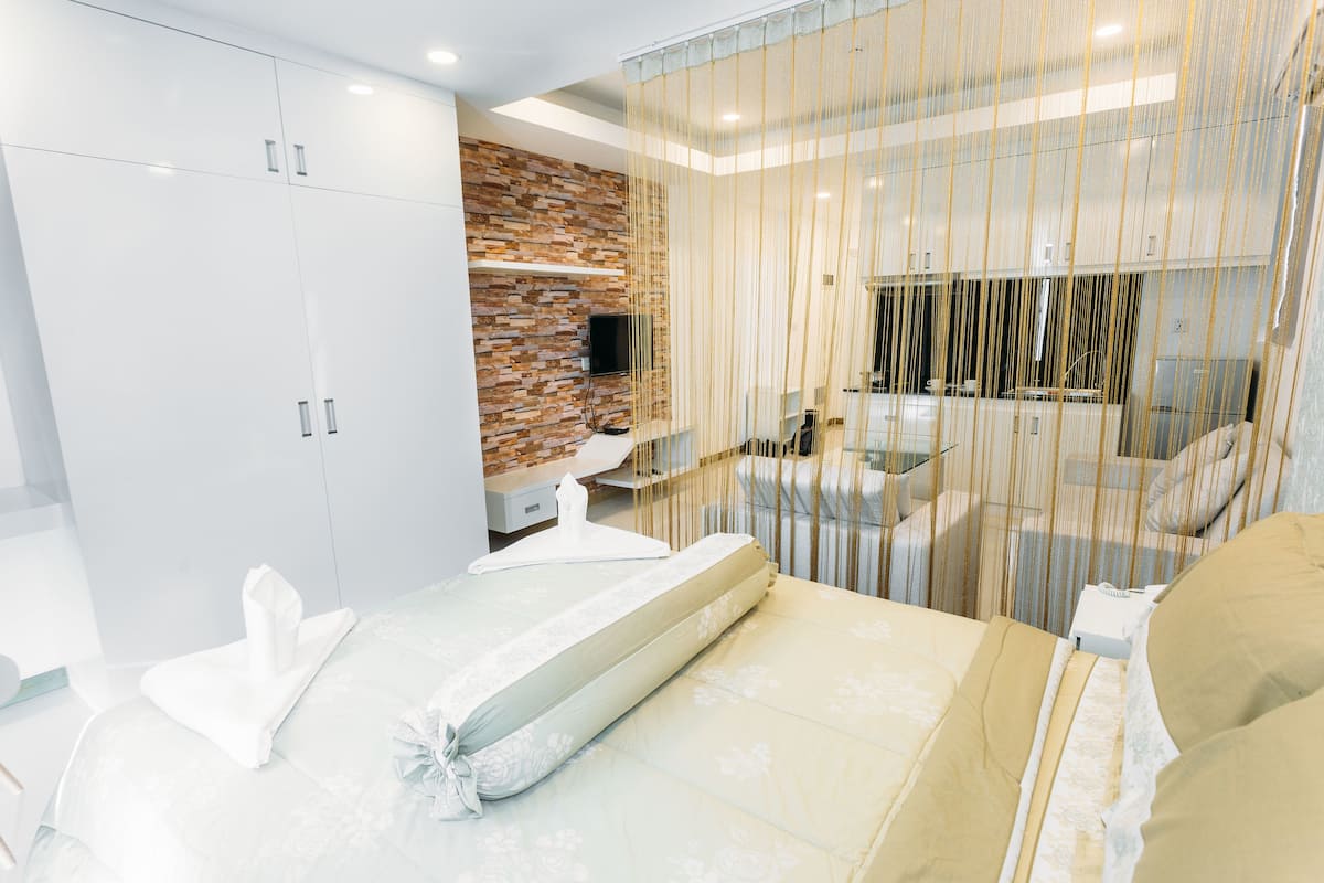 Ein modernes Hotelzimmer mit einem großen Bett, einer Sitzecke, einem Fernseher und einer Wand mit Ziegelmuster.