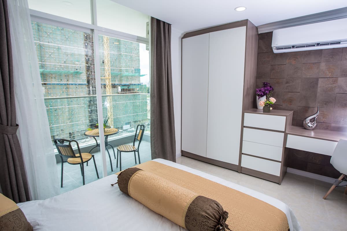 Ein Hotelzimmer mit Bett, Schreibtisch, Stuhl und einem Balkon mit Blick auf eine Baustelle.
