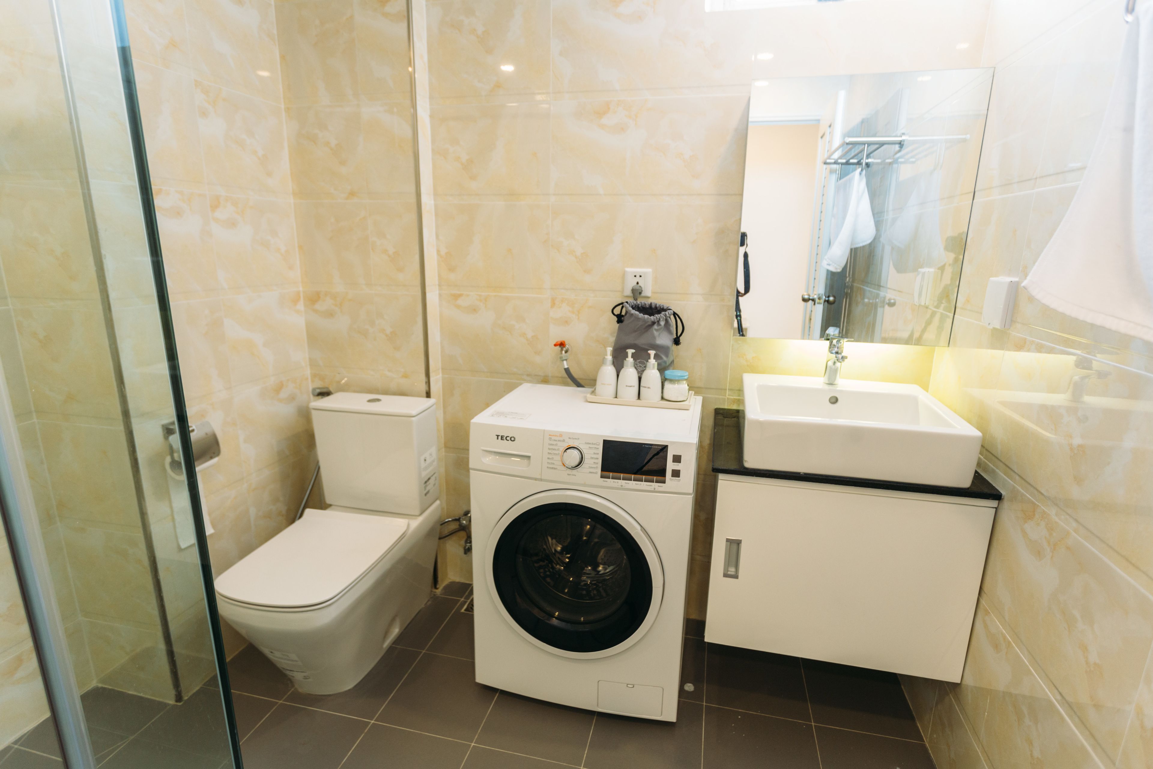 Une petite salle de bain comprenant des toilettes, un lave-linge et un lavabo.