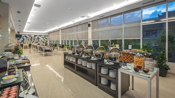 Un buffet moderne, avec différents postes de service pour les plats, un espace pour s’asseoir et de grandes fenêtres offrant une vue sur l’extérieur.