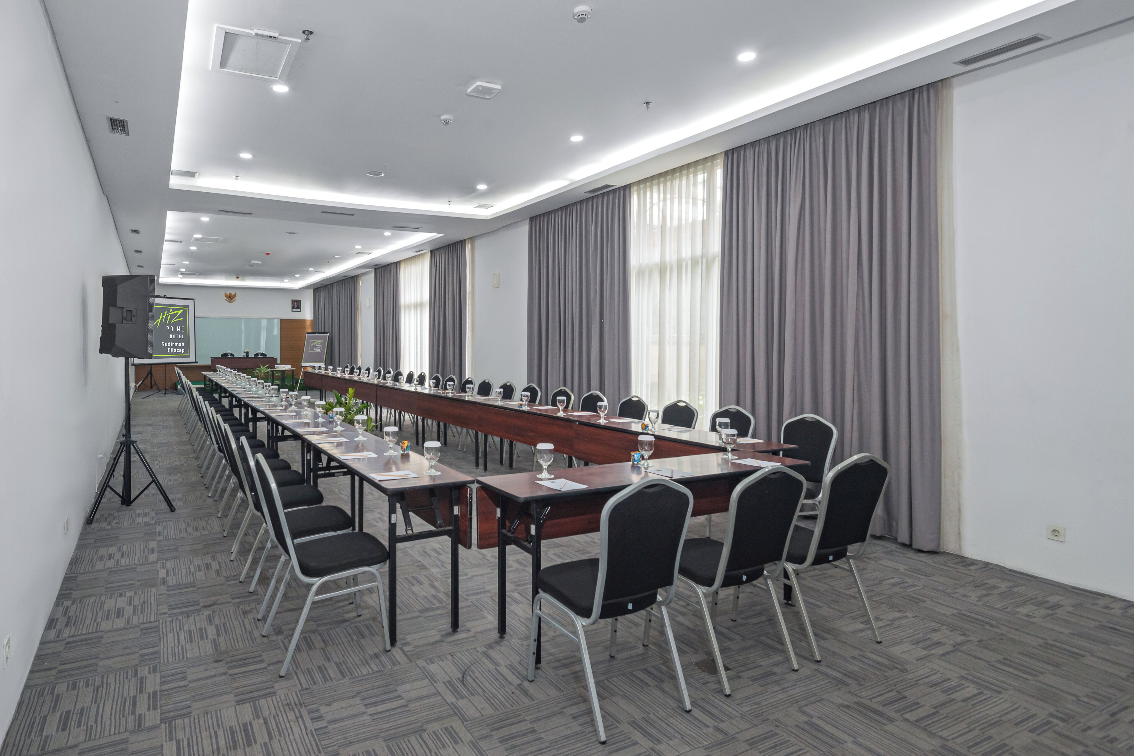 Una sala de conferencias con una larga mesa, sillas y una pantalla de proyector.