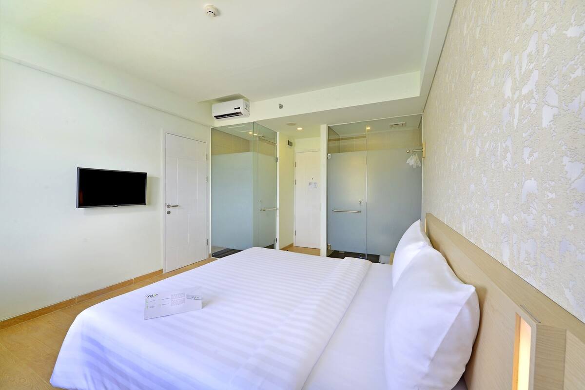 Ein Hotelzimmer mit Bett, Flachbildfernseher an der Wand und Spiegel.