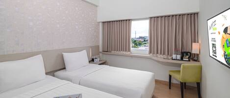 A hotel room with two beds, a desk, a chair, a window with curtains, and a wall-mounted screen displaying a loyalty program.