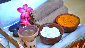 Ambiente spa con un asciugamano, un fiore e ciotole di sali da bagno e crema.
