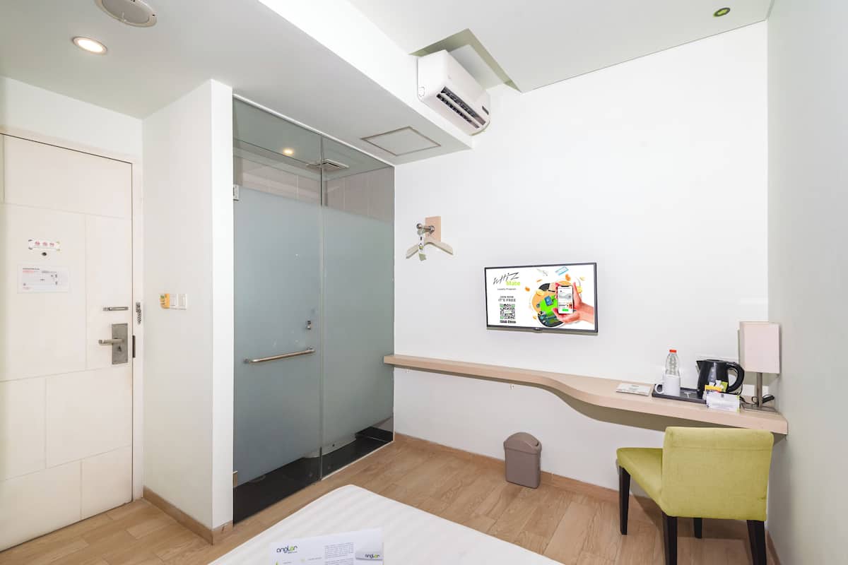Ein Hotelzimmer mit Schreibtisch, Stuhl und einer Glastür zum Duschbereich.