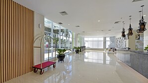 Un hall d’entrée spacieux avec un sol ciré, un comptoir d’accueil, des plantes en pot et un chariot.