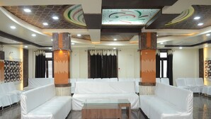 A spacious lobby with white sofas, a glass coffee table, and a patterned ceiling. - Hotel Rahil Palace (Varanasi)