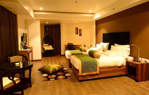 A hotel room with two beds, a dining table, a chair, a desk, a hanging chair, and a lamp.