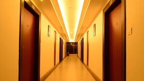 A hotel hallway with wooden doors and a warm, illuminated ceiling. - Hotel Shoolin Grand (Guwahati)
