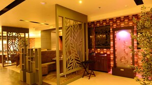 A modern interior with a sectional sofa, a decorative partition, and a seating area with a small table. - Hotel Shoolin Grand (Guwahati)